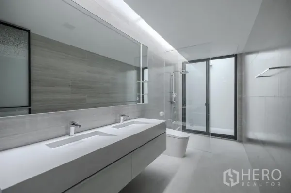 Detached House for rent in Saphan Sung, Bangkok - Contemporary bathroom with double sinks, large mirror and glass-enclosed shower.