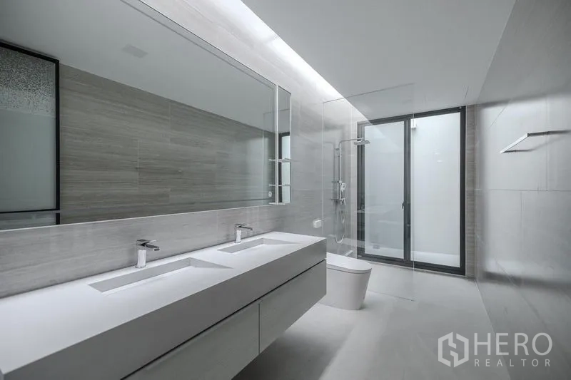 Detached House for rent in Saphan Sung, Bangkok - Contemporary bathroom with double sinks, large mirror and glass-enclosed shower.