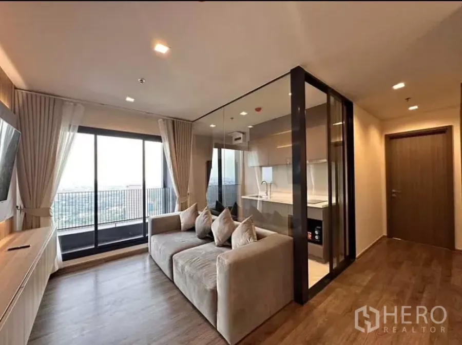 Condominium for rent in Chatuchak, Bangkok - Bright living room with floor-to-ceiling windows, balcony, and glass-partition kitchen at Life Ladprao Valley.