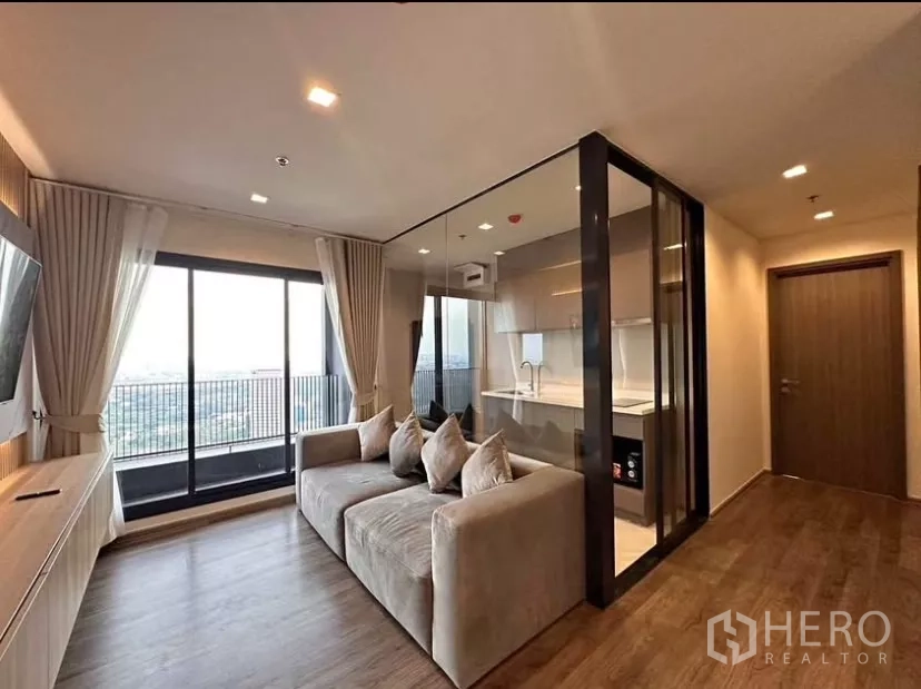 Condominium for rent in Chatuchak, Bangkok - Bright living room with floor-to-ceiling windows, balcony, and glass-partition kitchen at Life Ladprao Valley.