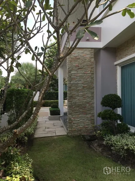 Detached House for rent or sale in Saphan Sung, Bangkok - Landscaped side garden with stone-clad pillar, shrubs and walkway.
