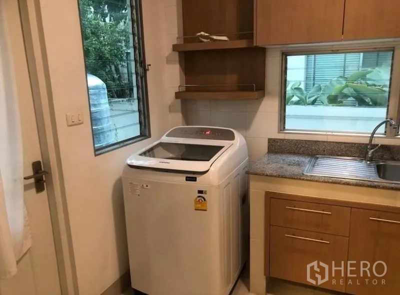 Detached House for rent in Prawet, Bangkok - Laundry and utility room with washing machine, sink and storage cabinets.