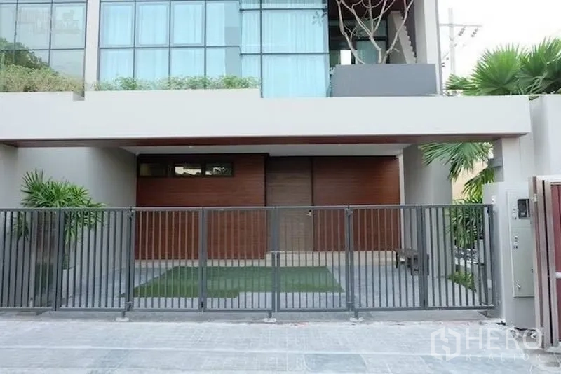 Townhouse for rent in Watthana, Bangkok - Modern townhouse facade with gated parking and floor-to-ceiling windows.