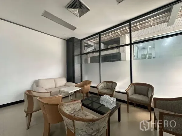 零售空间 出租 - 商业大楼内的接待区，沙发与扶手椅围绕茶几，旁为大面积磨砂玻璃窗。