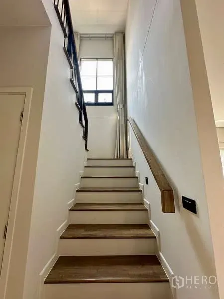 独立式住宅 出租在Bang Phli, Samut Prakan - 木质楼梯配扶手与高窗，引入自然光。