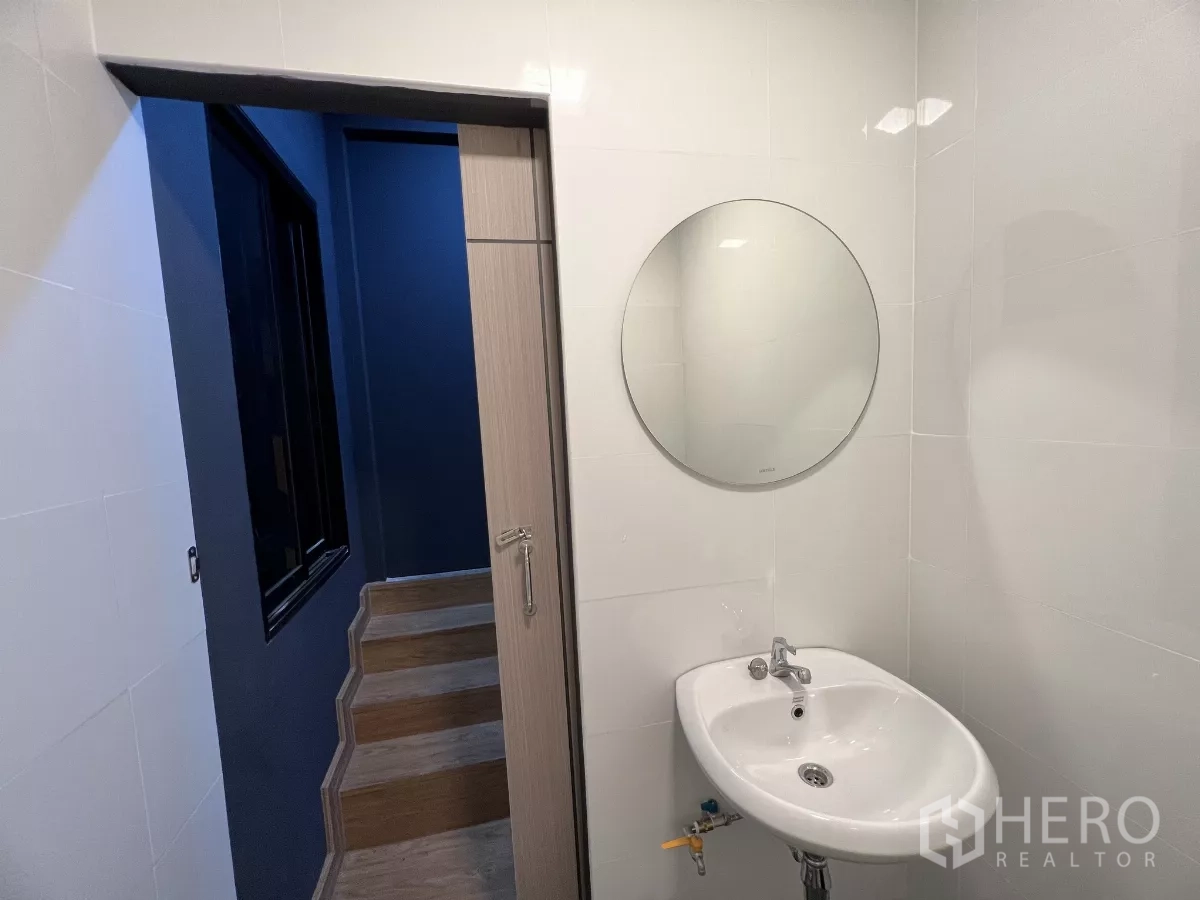 Home Office for rent in Pom Prap Sattru Phai, Bangkok - Round mirror above a white sink beside a sliding door and stairs.