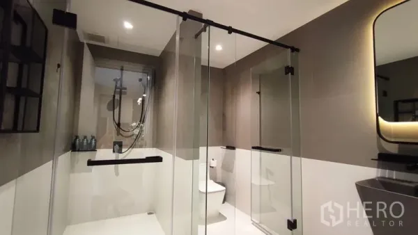 Condominium for rent in Bang Kho Laem, Bangkok - Contemporary bathroom with glass-enclosed rain shower, toilet and a backlit mirror.