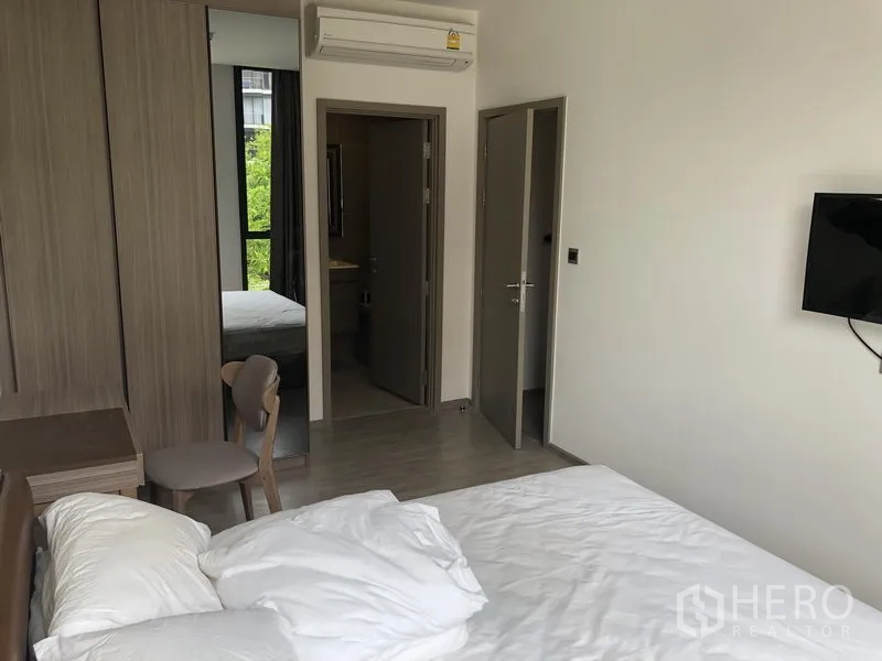 คอนโด ให้เช่าในWatthana, Bangkok - มุมห้องนอนใหญ่ไปยังตู้เสื้อผ้า โต๊ะทำงาน ทีวีติดผนัง และทางเข้าห้องน้ำในตัว