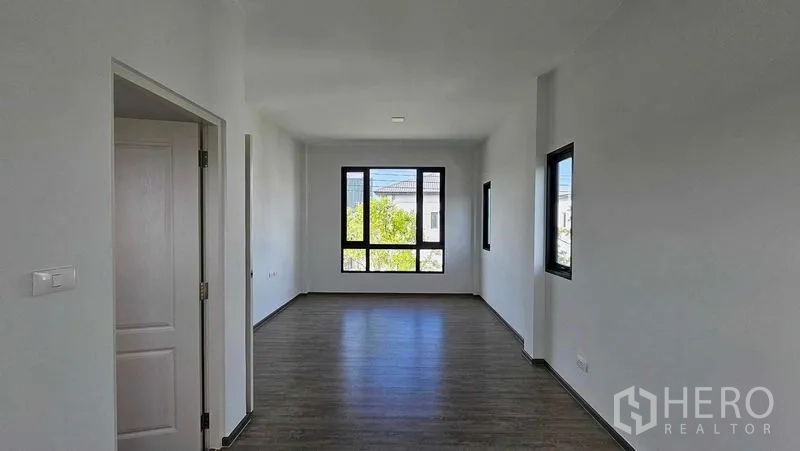Detached House for sale in Samut Prakan - Large bedroom with wood floors and wide windows bringing in natural light.