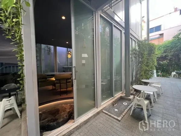 Retail Space for rent in Khlong Toei, Bangkok - Glass sliding doors opening to a small outdoor patio with café tables and surrounding greenery.