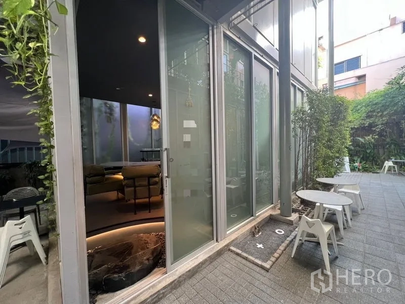 Retail Space for rent in Khlong Toei, Bangkok - Glass sliding doors opening to a small outdoor patio with café tables and surrounding greenery.