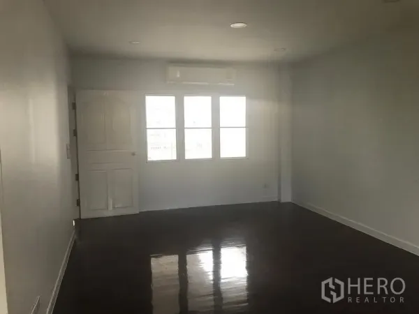 Home Office for rent or sale in Watthana, Bangkok - Large office room with glossy wood floors, split air-conditioner above the windows, and a white door.