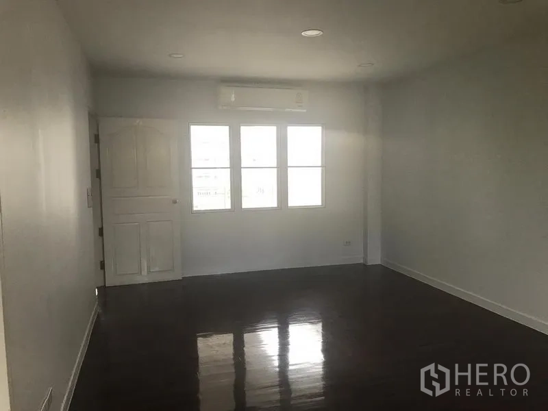Home Office for rent or sale in Watthana, Bangkok - Large office room with glossy wood floors, split air-conditioner above the windows, and a white door.
