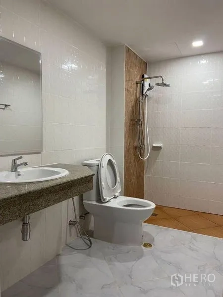 公寓 出租或出售在Watthana, Bangkok - 瓷砖卫浴，步入式淋浴、坐便器、大镜子与台面式洗手盆。