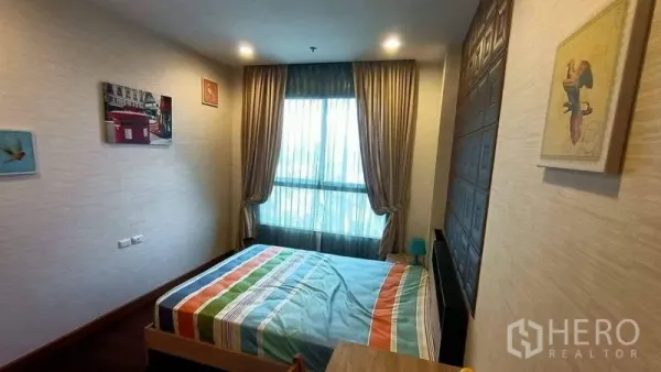 คอนโด ขาย - ห้องนอนขนาดกะทัดรัด เตียงผ้าปูสีสัน หน้าต่างใหญ่พร้อมผ้าม่าน