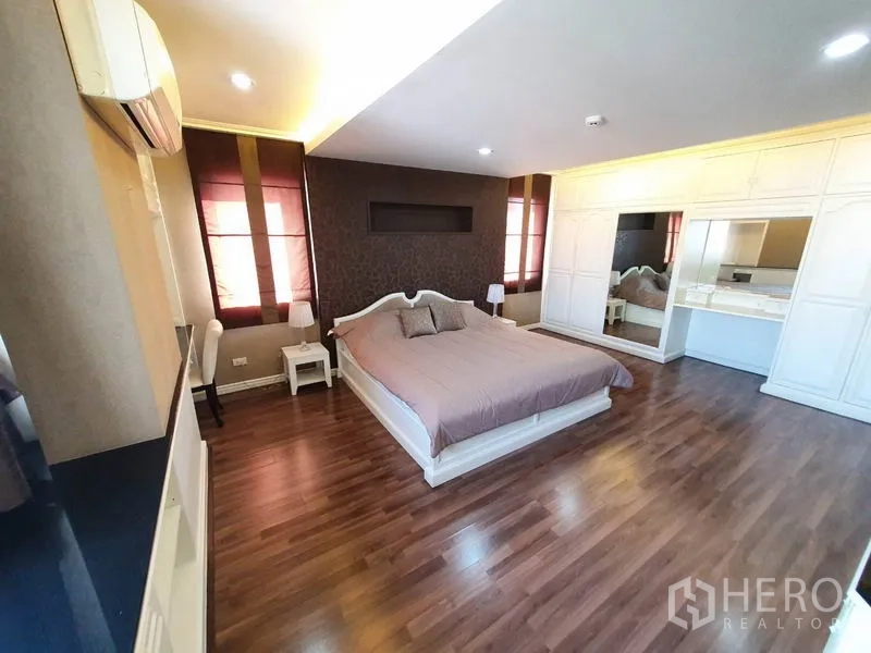 Condominium for rent in Watthana, Bangkok - Primary bedroom with king bed, wood flooring, and full-height wardrobes.