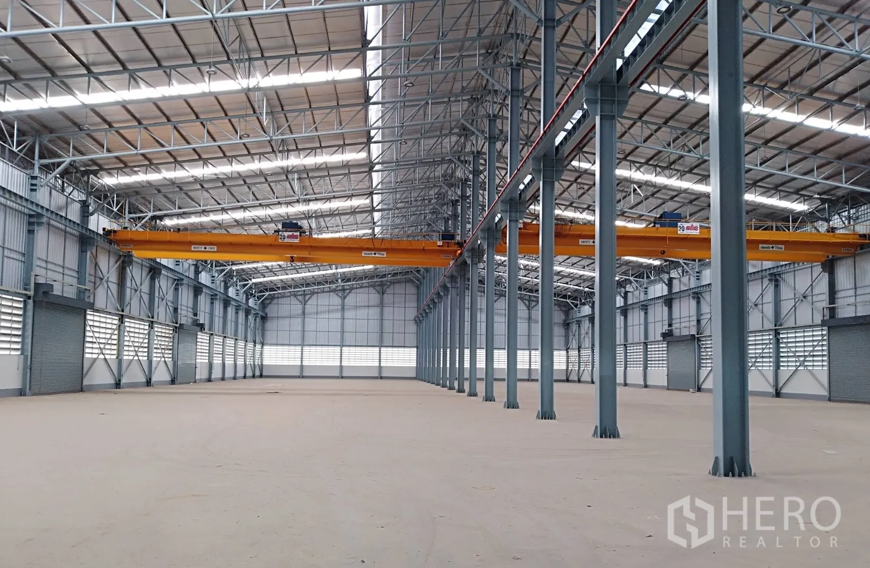 Warehouse for rent in Wang Noi, Phra Nakhon Si Ayutthaya - Spacious warehouse interior with steel columns, skylights, overhead gantry cranes, and roller shutter doors.