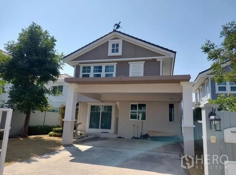 Detached House for rent in Bang Bo, Samut Prakan - Two-storey detached house with covered carport and front yard in a gated community.