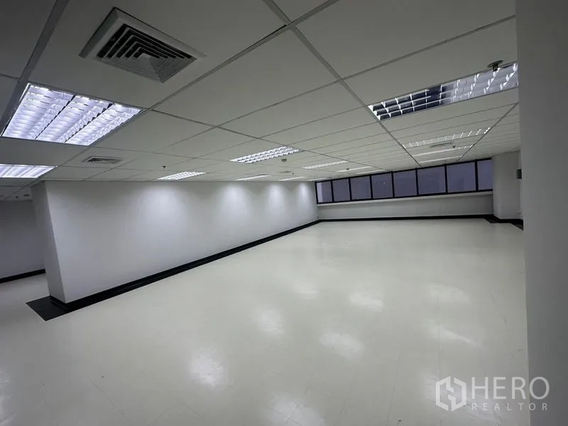 Office Space for rent - Spacious office area with light flooring, recessed grid lighting and extended windows providing natural light.