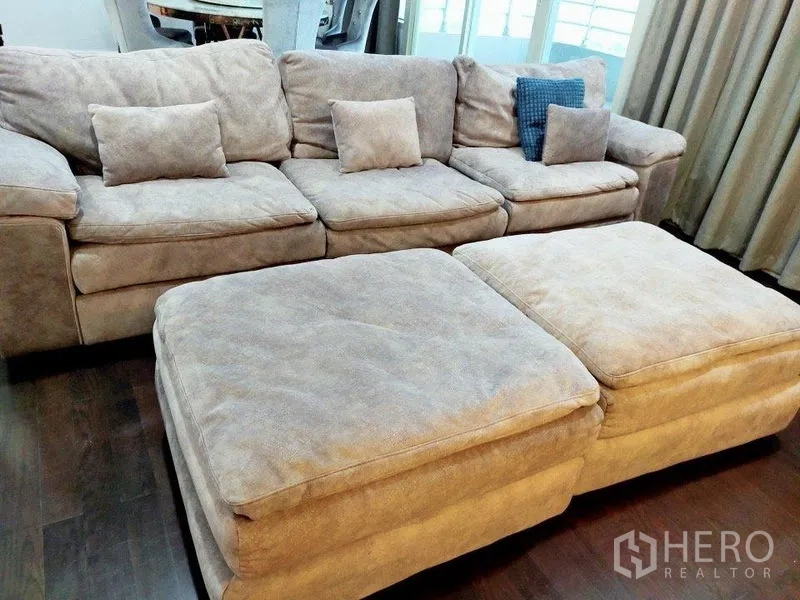 公寓 出租在Khlong San, Bangkok - 米色绒面组合沙发与两个脚凳的近景，深色木地板。