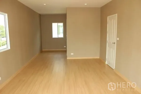 Detached House for rent in Saphan Sung, Bangkok - Long upstairs room with warm wood flooring, recessed lights and a white door.