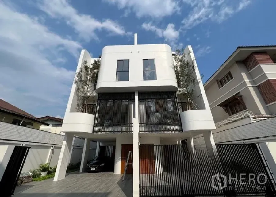 สำนักงานที่บ้าน ขายในPhra Khanong, Bangkok - ด้านหน้าบ้านโฮมออฟฟิศสีขาวโมเดิร์น พร้อมระแนงแนวตั้งและประตูรั้ว.