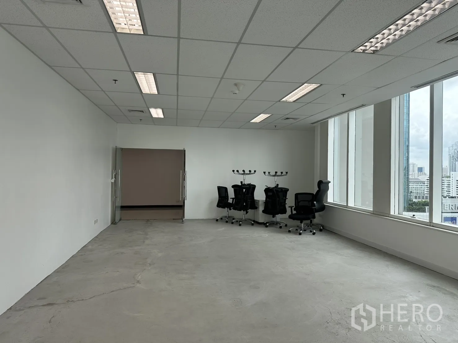 ออฟฟิศ for rent in Watthana, Bangkok - พื้นที่สำนักงานพร้อมประตูกระจกบานคู่ เก้าอี้ล้อเลื่อน และแสงธรรมชาติจากมุมหน้าต่าง.