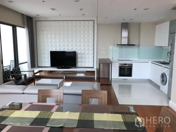 คอนโด ให้เช่าหรือขายในKhlong Toei, Bangkok - ห้องนั่งเล่นแบบเปิดโล่งพร้อมผนังทีวี ครัวสีขาวสมัยใหม่ และพื้นไม้