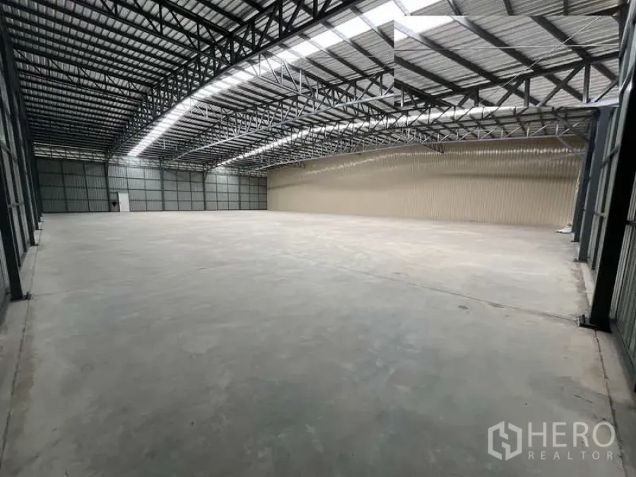 Warehouse for rent or sale in Pak Kret, Nonthaburi - Spacious warehouse interior with high steel truss roof, skylight strips, and polished concrete floor.