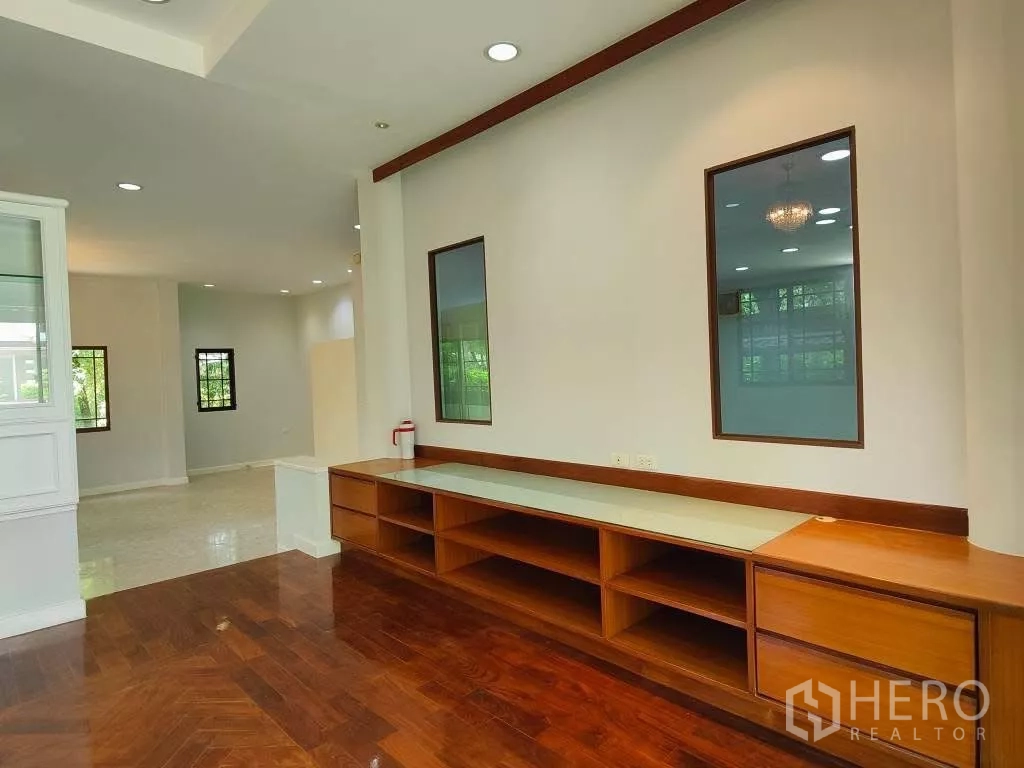 独立式住宅 出租或出售在Mueang Nonthaburi, Nonthaburi - 木地板客厅，长条内置电视柜与装饰窗户。