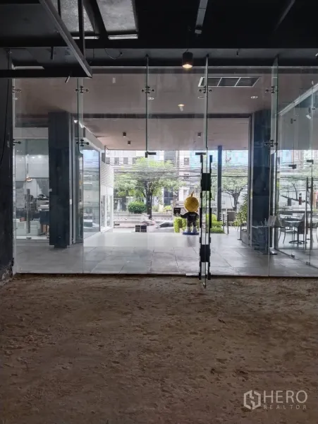 พื้นที่ขายปลีก ให้เช่าในKhlong Toei, Bangkok - หน้าร้านกระจกเต็มบานเปิดสู่ลานมีหลังคาและทิวทัศน์ถนนด้านหน้า.