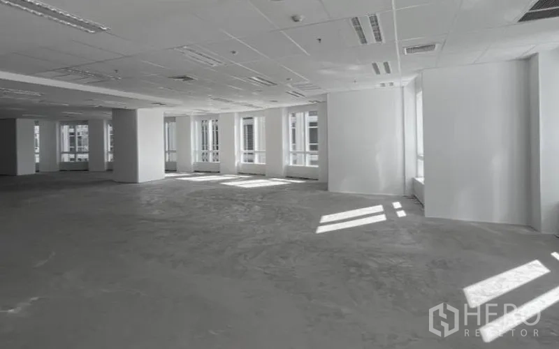 Office Space for rent - Bright open-plan office floor with white walls, drop ceiling lighting, and large windows.