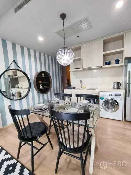 คอนโด ให้เช่าในBangkok - มุมรับประทานอาหารสว่างพร้อมโต๊ะกระจก เก้าอี้สีดำ โคมไฟ และครัวเปิดขนาดกะทัดรัดพร้อมเครื่องซักผ้า