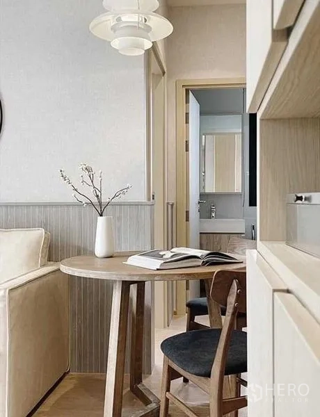 Condominium for rent in Watthana, Bangkok - Compact dining nook with wooden table, pendant light and vase, facing the bathroom entrance.