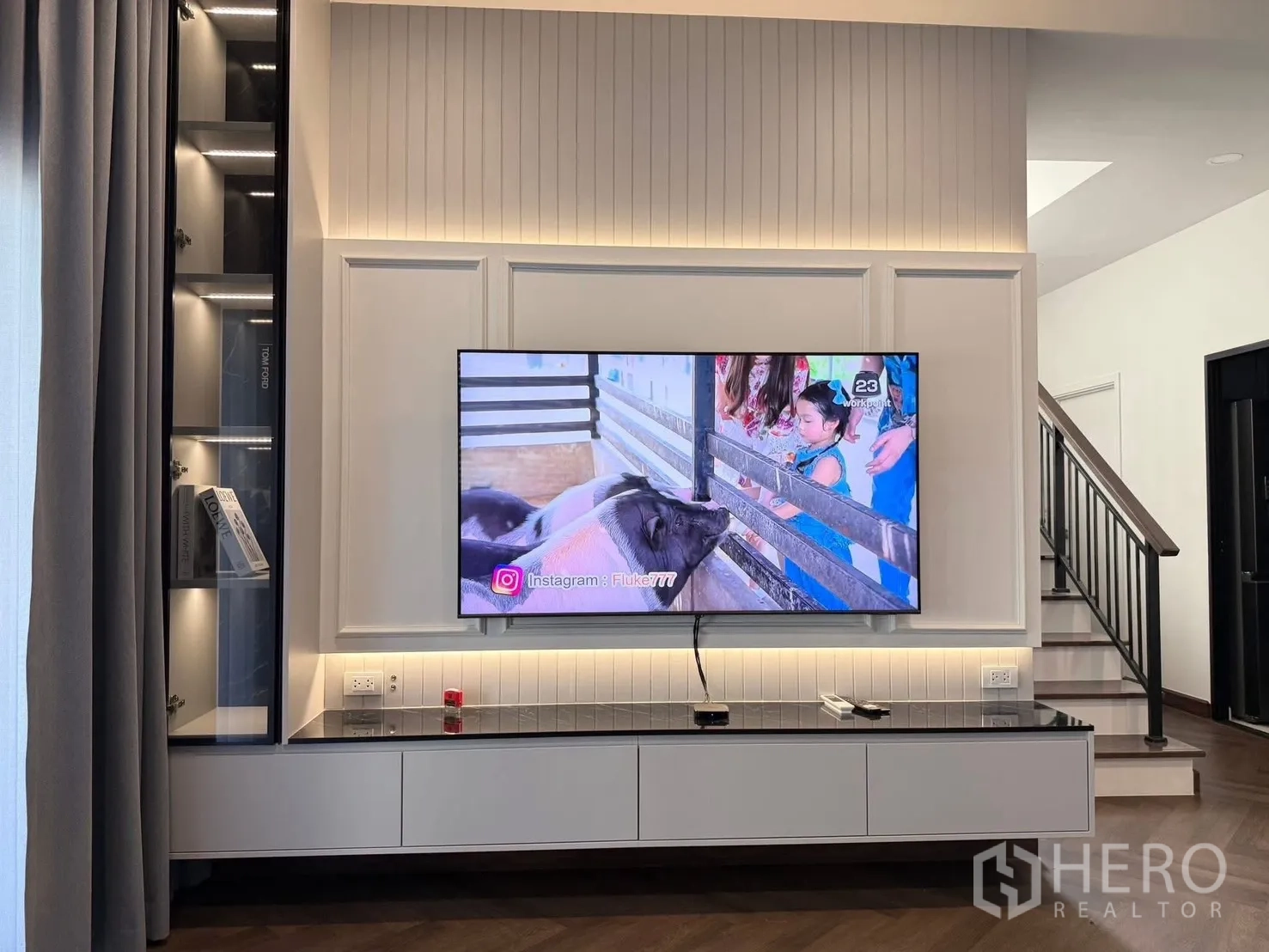 Detached House for rent in Bang Phli, Samut Prakan - Living room feature wall with mounted TV, shelving and a staircase nearby.