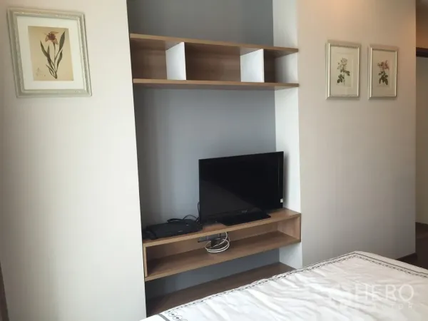 Condominium for rent or sale in Watthana, Bangkok - Bedroom media shelf with flat-screen TV and wall art for storage and display.