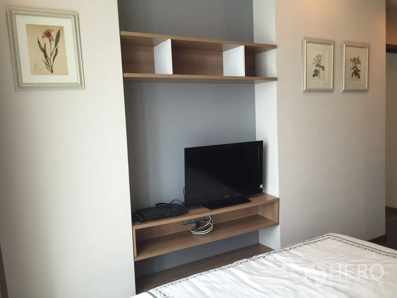 Condominium for rent or sale in Watthana, Bangkok - Bedroom media shelf with flat-screen TV and wall art for storage and display.