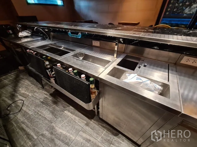 零售空间 出租在Bang Rak, Bangkok - 吧台下方不锈钢工作站，带水槽、制冰槽与酒瓶储位。