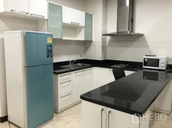 คอนโด ให้เช่าในKhlong Toei, Bangkok - ครัวรูปตัวแอล เคาน์เตอร์หินสีดำ เครื่องดูดควัน เกาะครัว และตู้เย็นสองประตูสีฟ้า