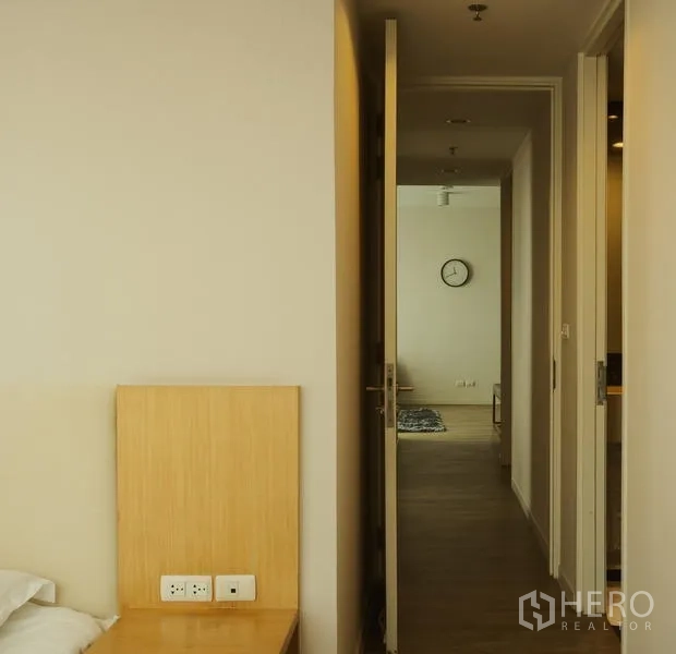 公寓 出租在Bang Rak, Bangkok - 从卧室通往客厅的走廊，木地板与挂墙时钟