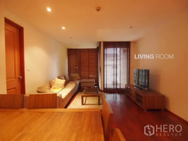 Condominium for rent in Pathum Wan, Bangkok - Living room with sectional sofa, TV console and sliding doors to the balcony.