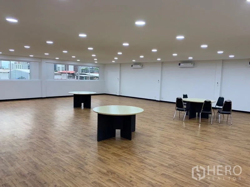 Office Space for rent in Khlong Toei, Bangkok - Open office area with multiple round tables, large windows and several AC units.