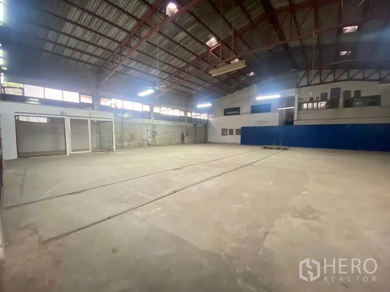 Warehouse for rent or sale in Suan Luang, Bangkok - Wide interior bay with side windows, suspended lights and ample floor area for storage or light production.