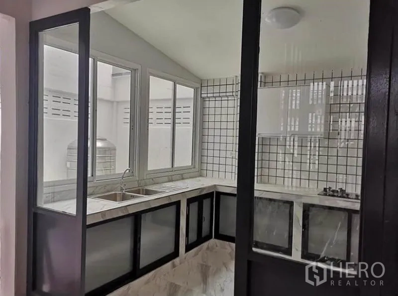 联排别墅 出租或出售在Din Daeng, Bangkok - 厨房另一角，窗边双槽水槽与玻璃隔断门。