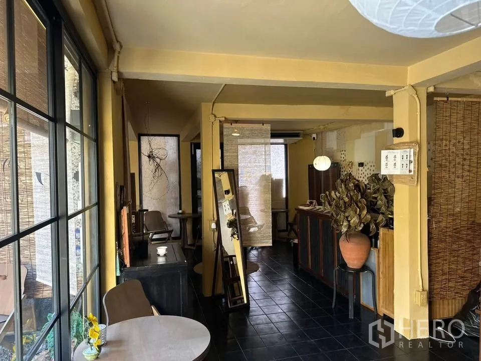 พื้นที่ขายของ for rent in Khlong Toei, Bangkok - โถงภายในคล้ายแกลเลอรี มีหน้าต่างบานใหญ่ โต๊ะเล็ก และชั้นวางภายใต้แสงไฟอบอุ่น