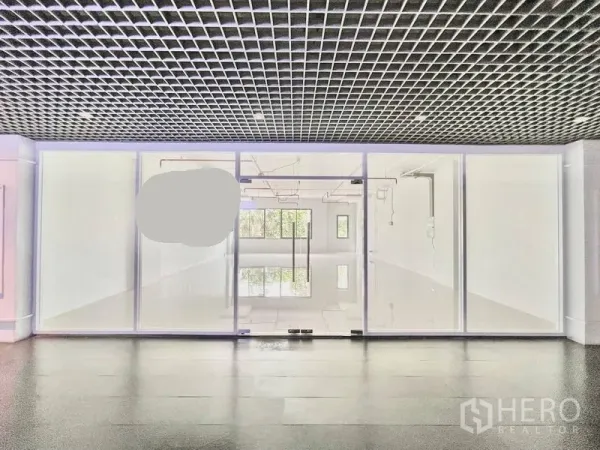Office Space for rent in Khlong Toei, Bangkok - Lobby view of the office entrance featuring full-height glass doors and a modern grid ceiling with daylight visible through interior windows.