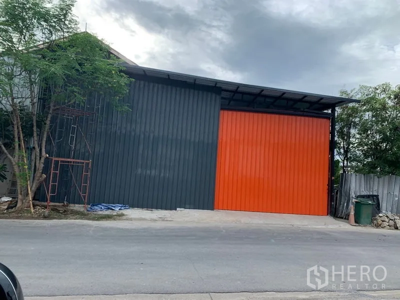 คลังสินค้า ให้เช่าในBang Kapi, Bangkok - มุมมองจากถนน เห็นประตูบานเลื่อนสีส้มขนาดใหญ่และผนังสีเทา