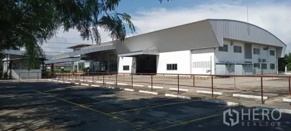 货栈 出租或出售在Lam Luk Ka, Pathum Thani - 现代金属屋顶仓库外观，宽阔混凝土场地与划线停车位