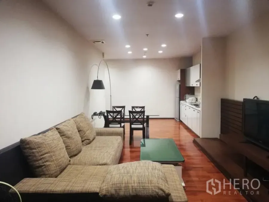 Condominium for rent in Watthana, Bangkok - Open-plan living room with sectional sofa, TV console, dining set and recessed lights.