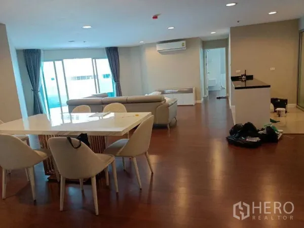 Condominium for rent or sale in Huai Khwang, Bangkok - Spacious living room with floor-to-ceiling windows, dining set and kitchen counter.
